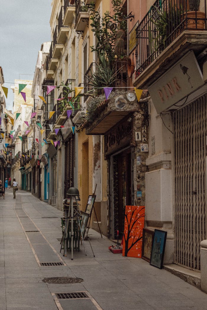 Charming street scene in Badajoz, Spain with cobblestones, flags, and colorful buildings.